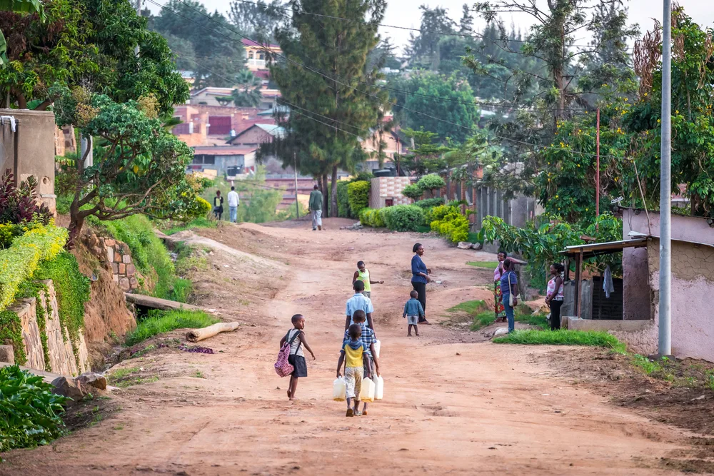 People walking down the street carrying water at a little village in Kigali