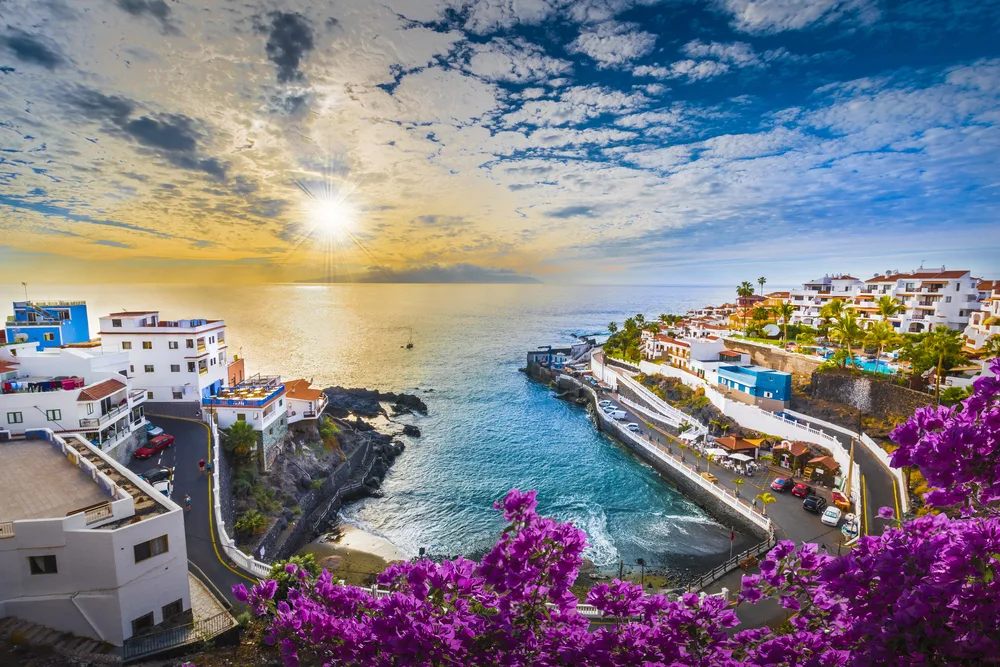 Amazing sunrise view of Tenerife and the resorts overlooking the ocean and a rocky black coastline pictured during the best time to go to the Canary Islands