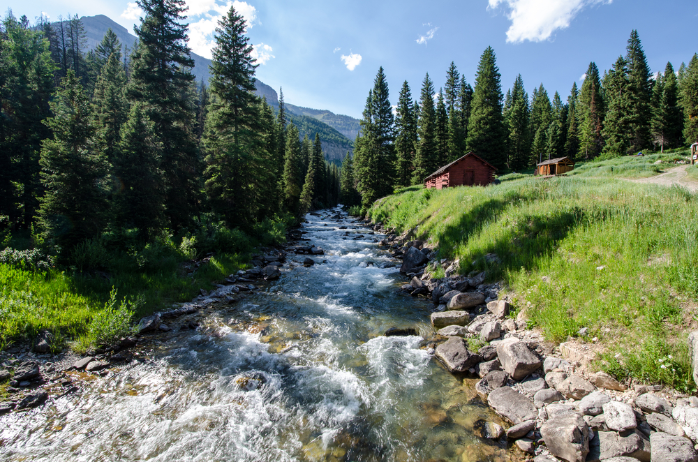 River flowing down the middle of the mountains and next to a cabin during the best time to visit Jackson Hole, the spring