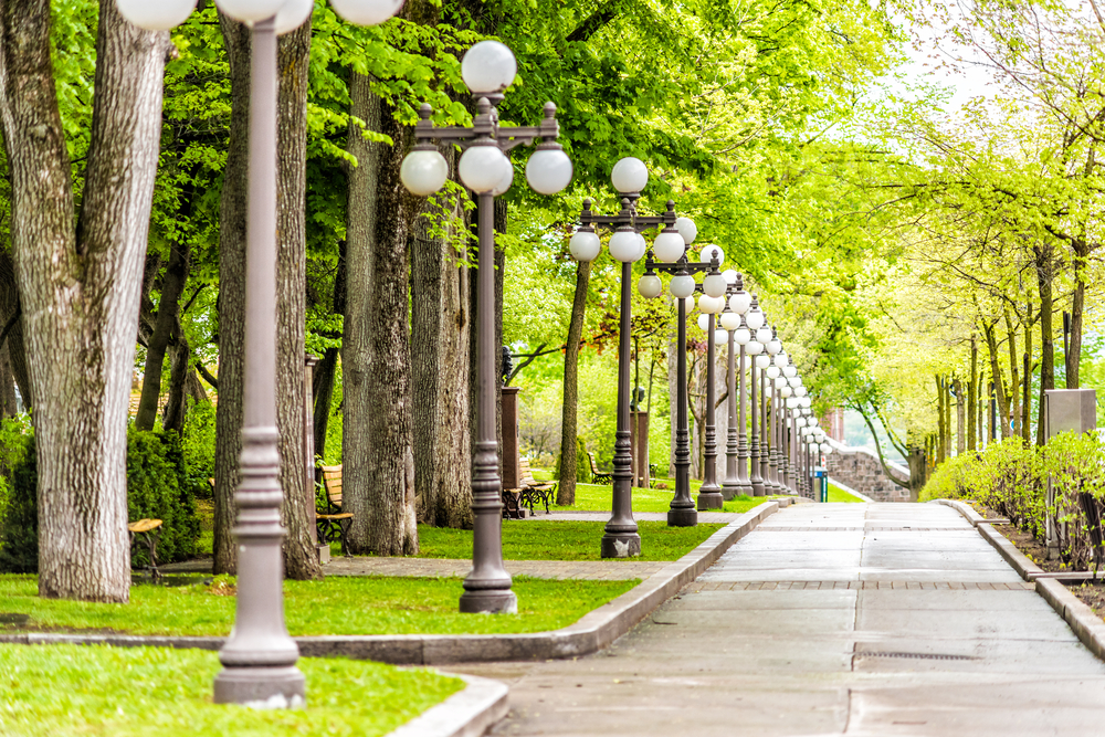 Grande Allee sidewalk with a row of lamps in a park during the cheapest time to visit Quebec City