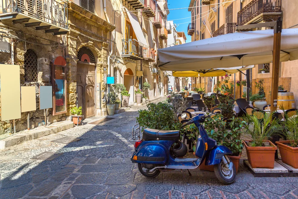 Narrow street in the town of Cefalu pictured during the best time to visit Sicily, the summer