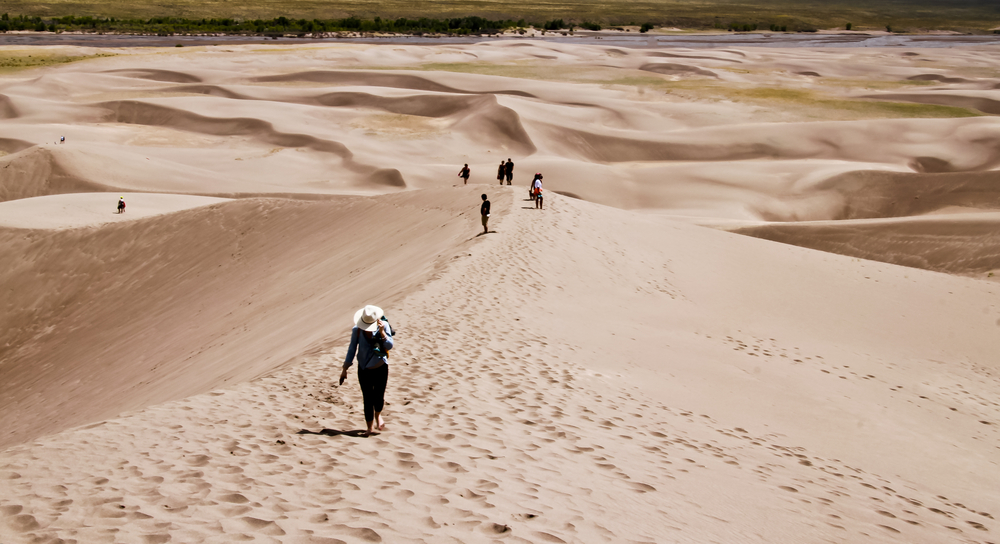 Several people hiking on the Great Sand Dunes National Park while walking down the hill of sand