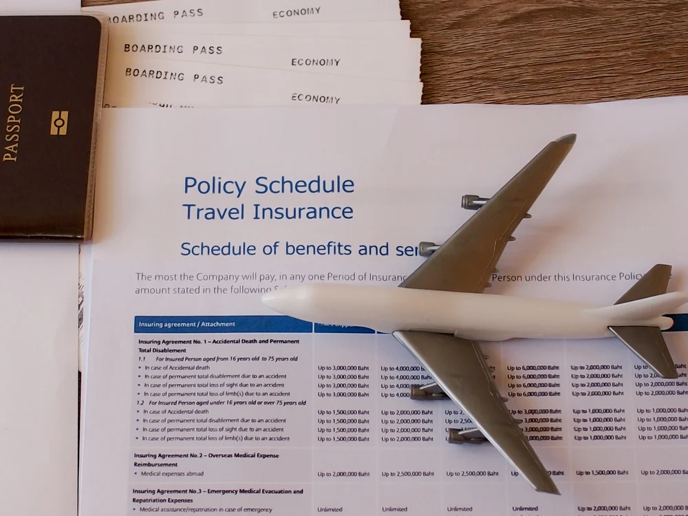 Image of airplane model resting on a travel insurance policy and benefits schedule for a piece on the best travel insurance plans
