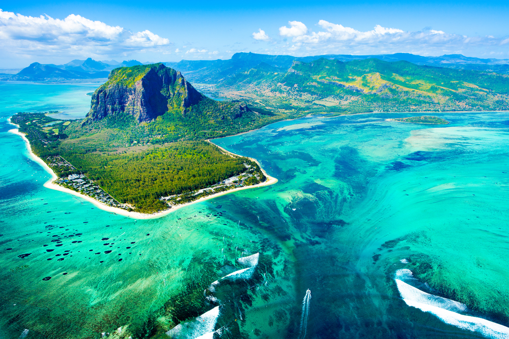 Gorgeous blue water and deep green vegetation on the volcanic island of Mauritius, as seen from a plane, for a guide to answer "is Africa safe to visit?"