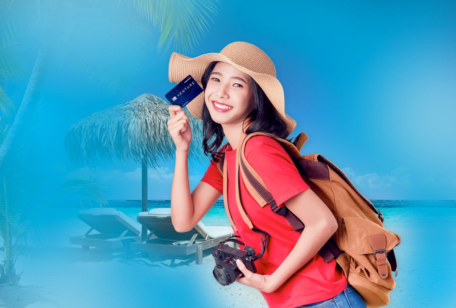 Featured image showing a woman holding one of the best travel credit cards, the Capital One Venture Rewards card, to her face with a camera around her neck