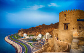 Hilltop landscape of Mutrah Corniche in Muscat, pictured during the best time to visit Oman with still water and blue sky