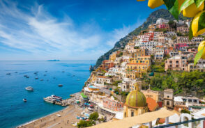 Hillside view of the picturesque town of Positano pictured during the spring, the best time to visit, with few people on the beaches below and still water and blue skies overhead