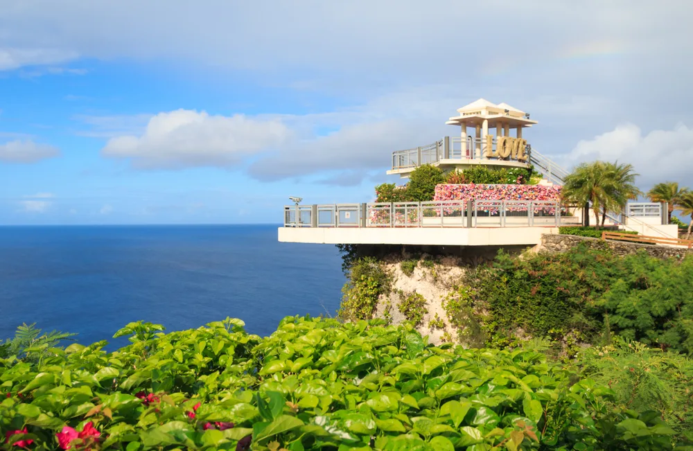 Neat observation point with a deck at the Two Lovers Point pictured during the best time to visit Guam with blue skies and blue water beyond the structure