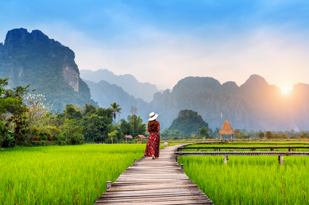 Young woman walking on a wooden boardwalk in Vang Vieng during the best time to go to Laos
