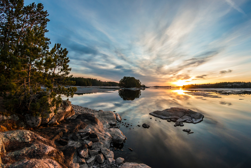 Sunrise over Voyageurs National Park as seen from the bank of a lake during the best time to visit Minnesota