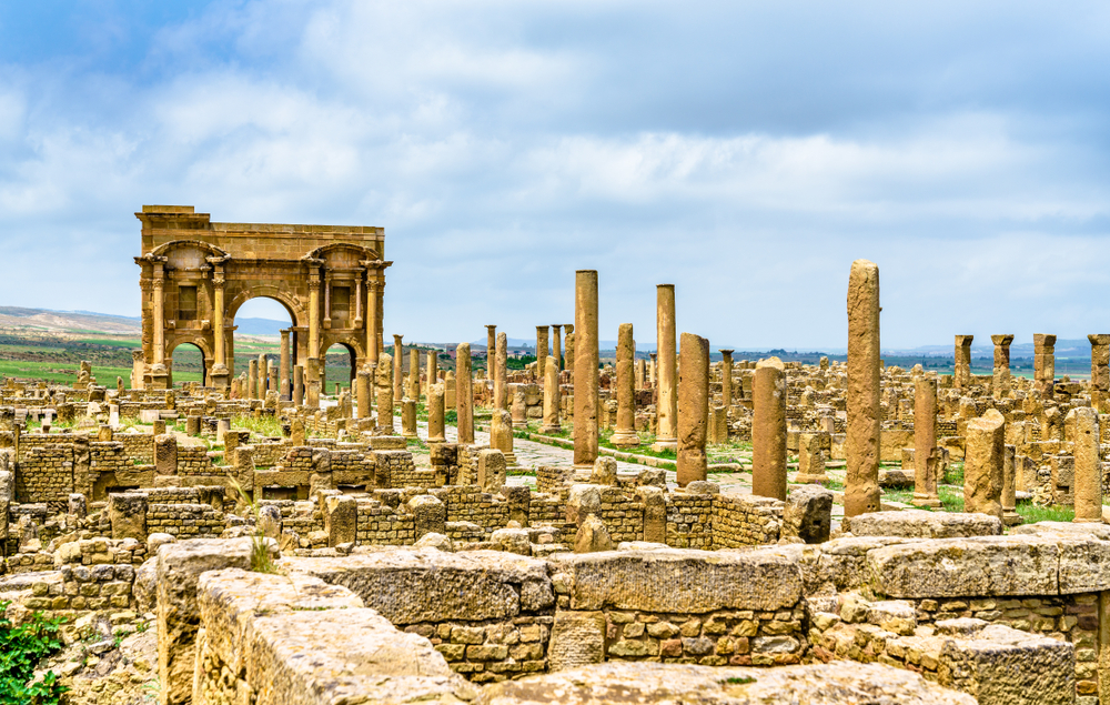 The historical ruins of Timgad with a wall and an old temple pictured for a piece titled Is Algeria Safe to Visit
