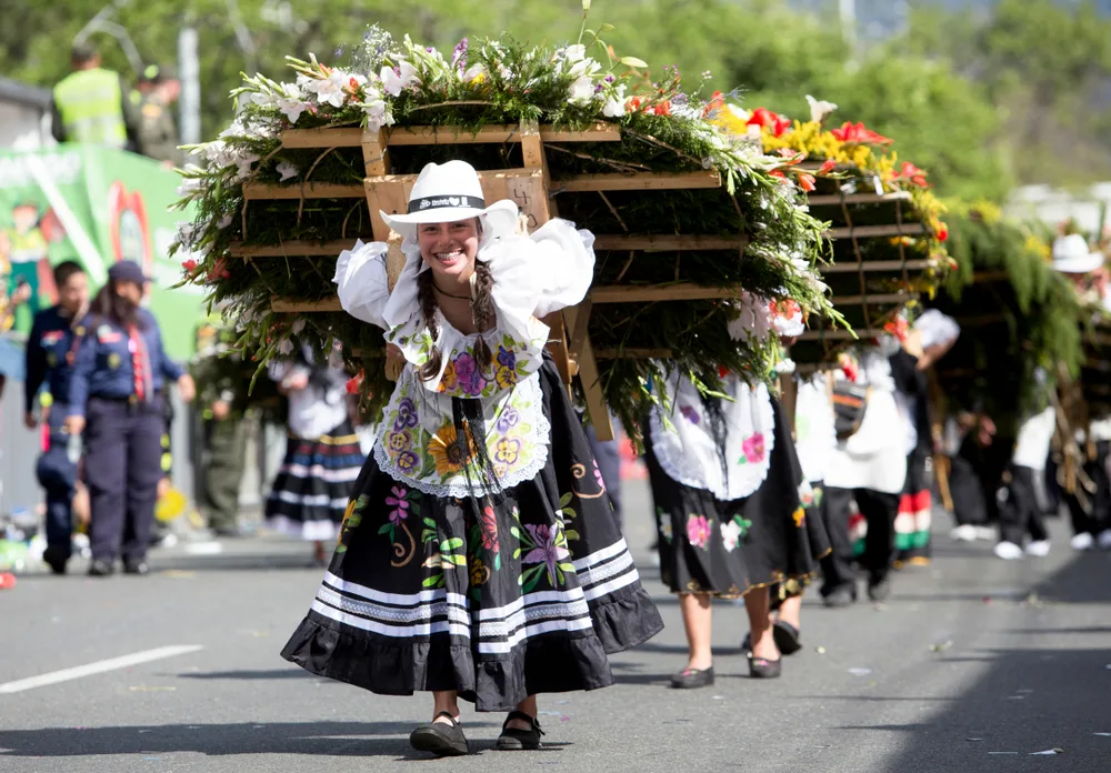 Women carrying flowers on their back in August during the Flower Festival, one of the best times to visit Medellin