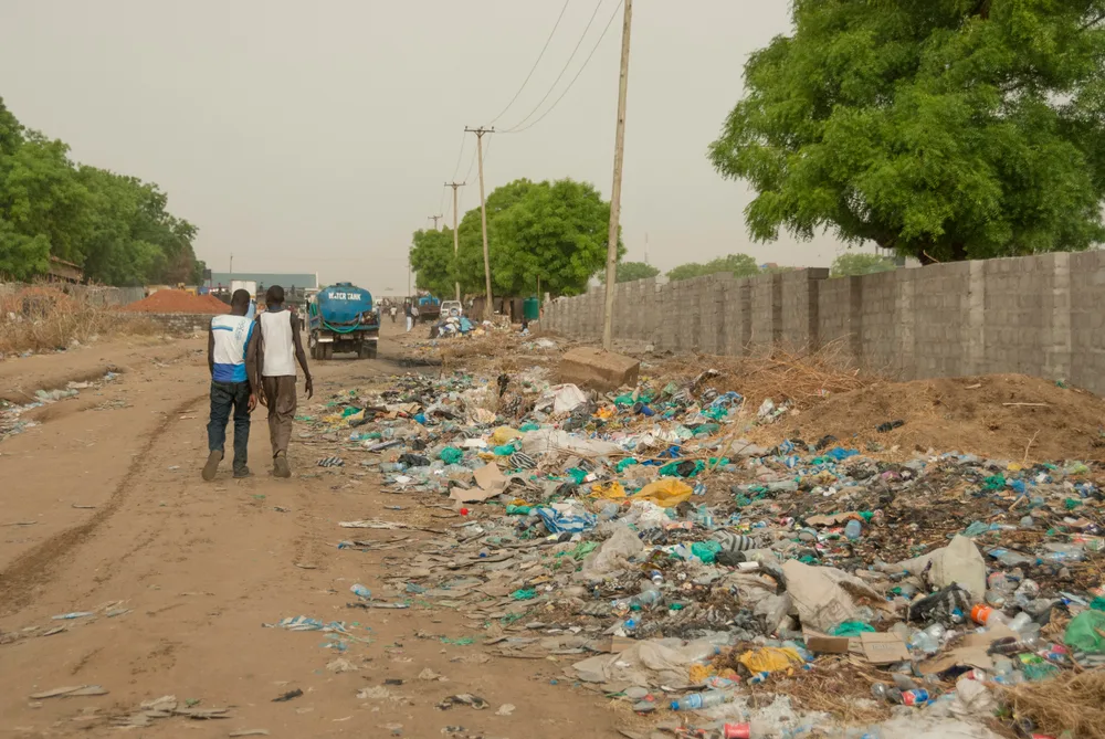 Two Sudanese kids walking by a garbage pile for a piece on is Sudan safe to visit