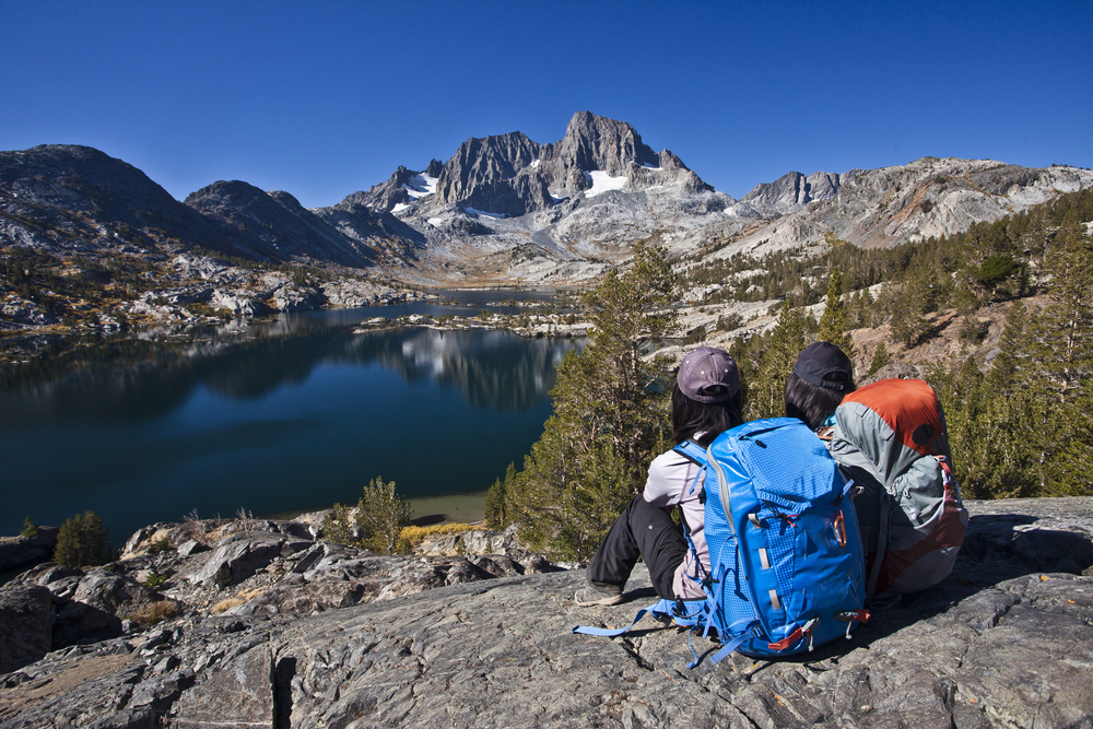Two girls sitting on a rock overlooking a lake during the overall cheapest time to visit the Mammoth Lakes