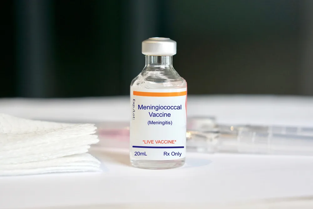 Meningococcal vaccine ciao with syringe lying behind it on a white counter for a piece on vaccines needed to travel to Africa