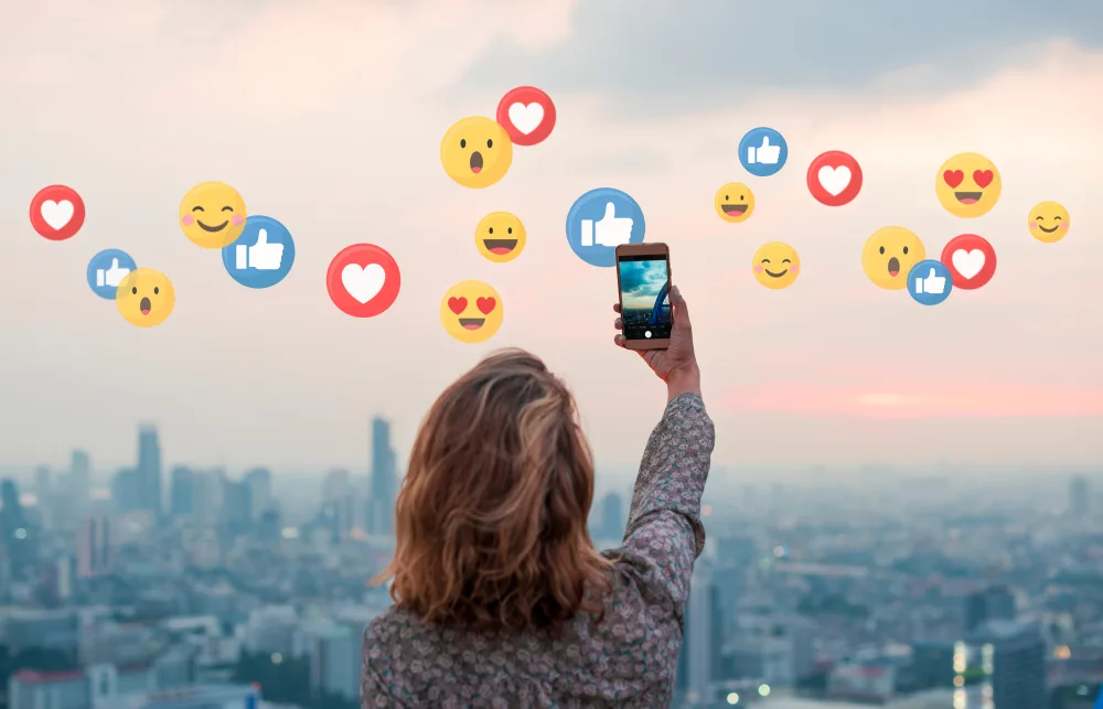 Idea for how to get paid to travel featuring a woman taking a selfie in front of a city skyline at sunrise while traveling with emojis around her