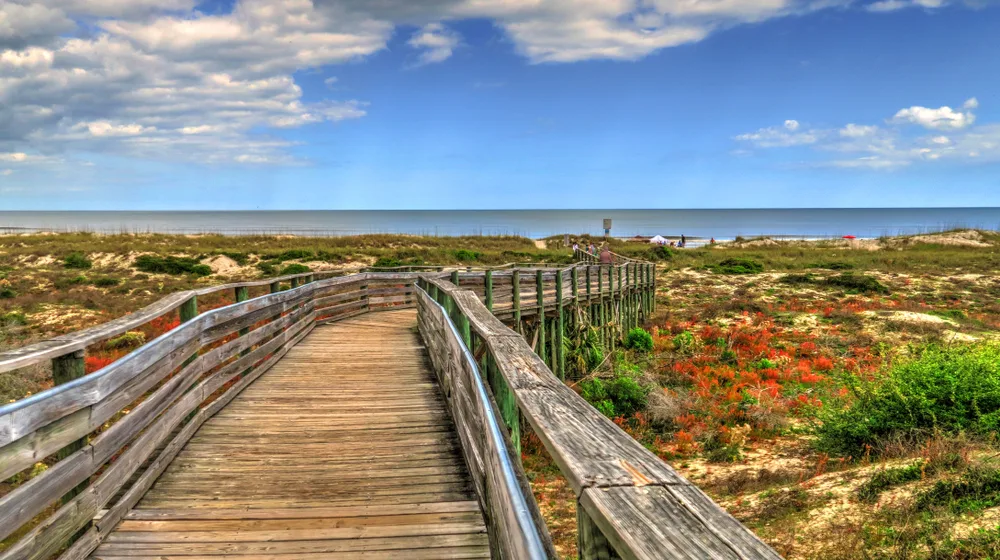 Long wooden boardwalk leading down to the sandy beach pictured during the least busy time to visit Amelia Island with nobody in sight
