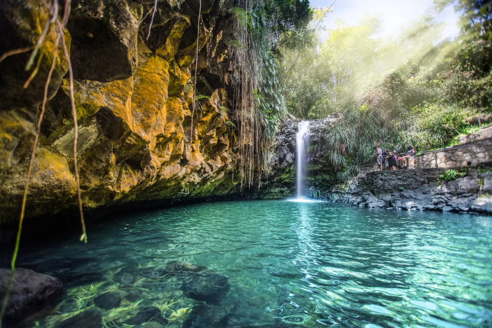 Neat daytime view of Annandale Falls in Grenada pictured with water falling into a gorgeous teal water pool with vegetation and rocks all around