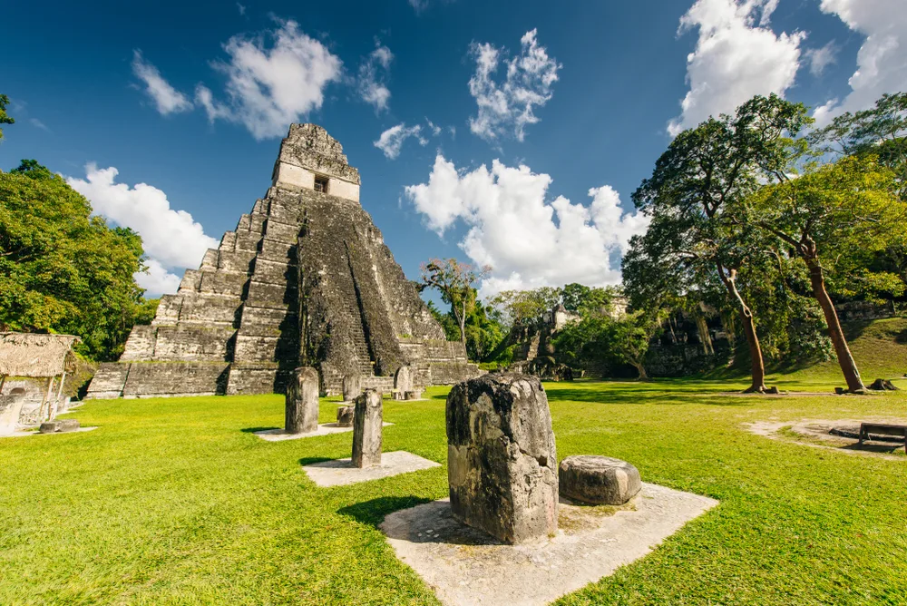 Mayan ruins of Tikal, one of the best places to visit in Guatemala, pictured towering over the green grass