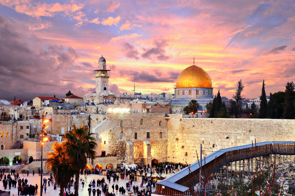 Dusk view of Jerusalem and its Old City wall outside of the Temple Mount with a golden mosque roof in the background