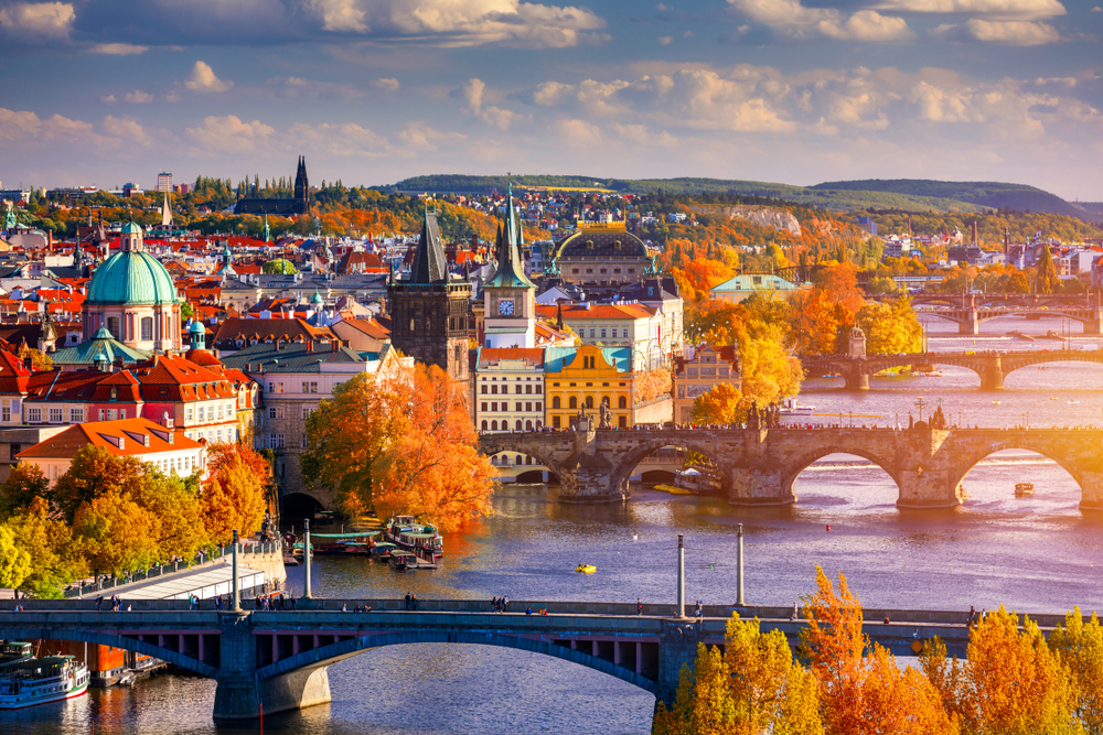 Picturesque aerial view of Prague seen over the river with trees turning golden red for a piece on the best places to visit in October