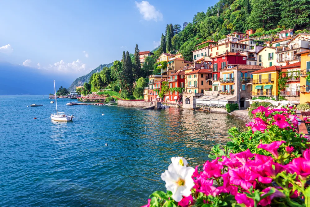 View of Lake Como pictured during the best time to visit Italian Lakes in the late spring, with flowers blooming and boats on the water