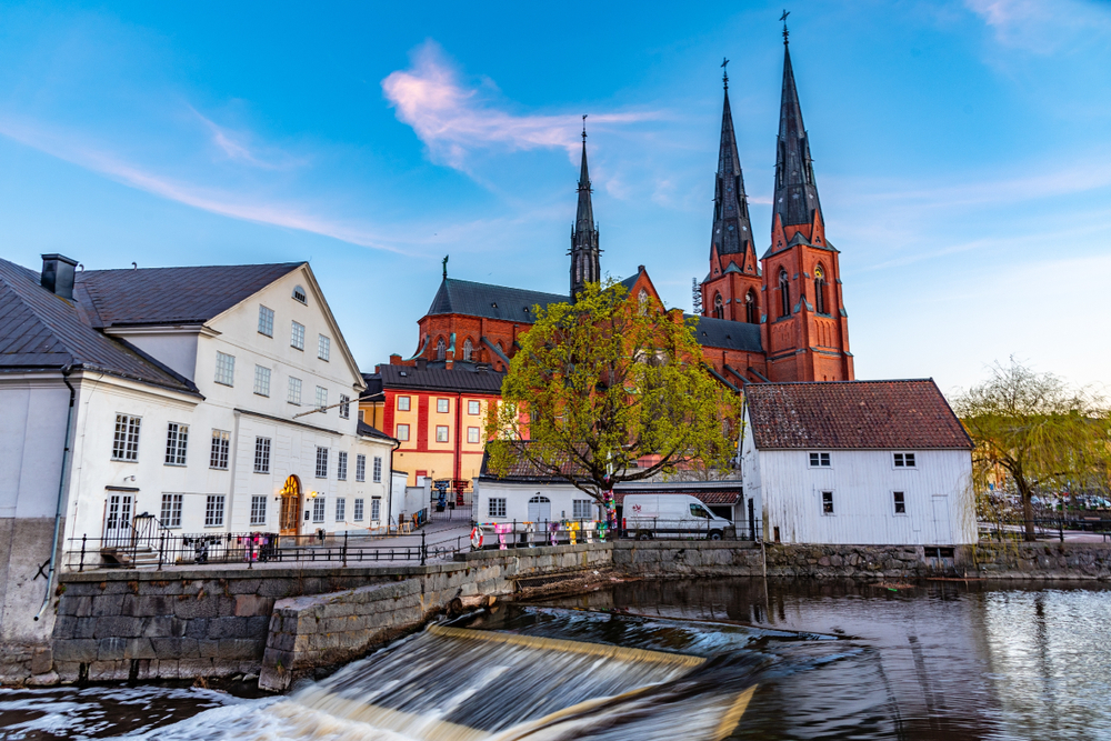 Idyllic town of Uppsala, as seen from the bank of the river by the waterfall with the cathedral and old homes towering over the water