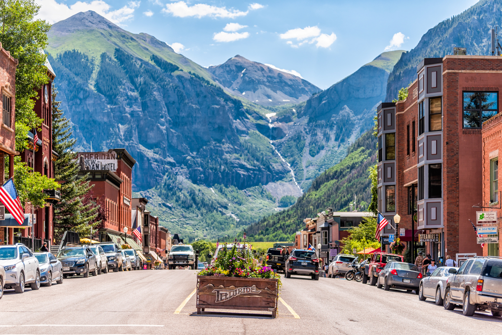 Photo of downtown Telluride, one of the best places to visit in July, with the mountains towering over the town