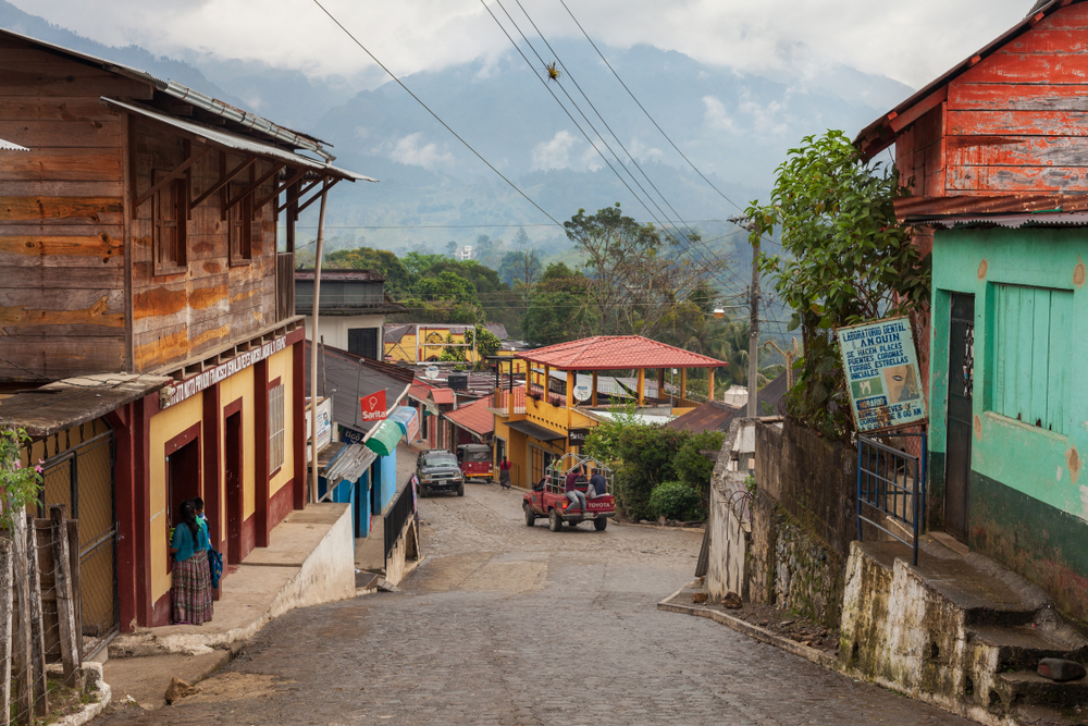 Small village of Lanquin, one of our top picks for places to visit in Guatemala, as seen from the street with old vehicles moving down the road