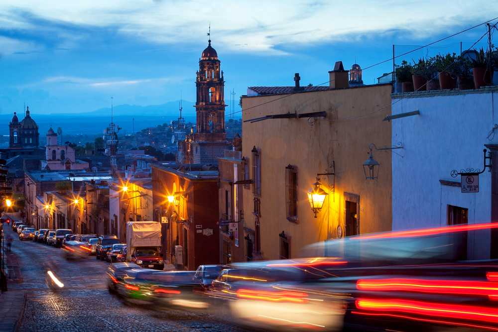 Night view of cars driving by a building in San Miguel de Allende during the city's worst time to visit