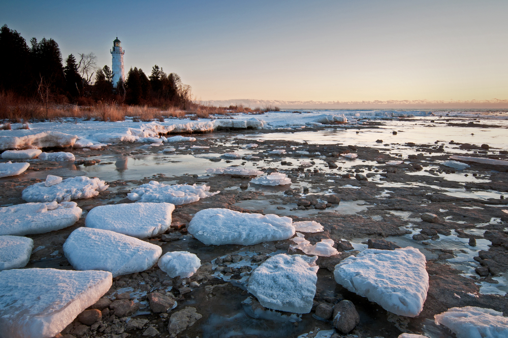 Early morning on the coast of the lake by the Cena Island Lighthouse during the cheapest time to visit Door County