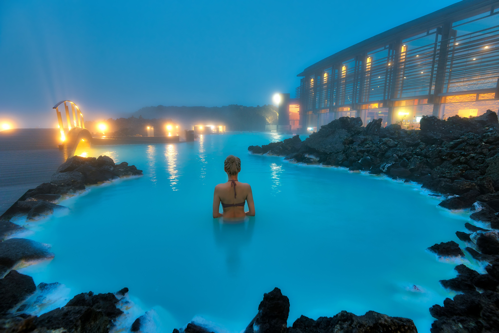 Thin woman in a bikini standing in the Blue Lagoon during the area's cheapest time to visit