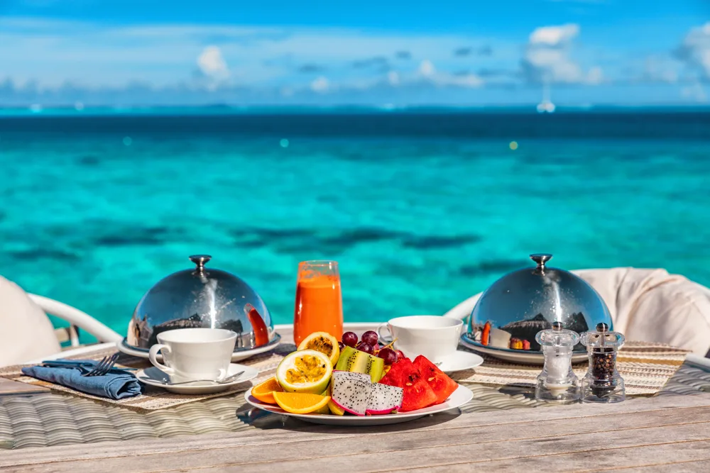 Waterfront luxury dining experience with table set for breakfast to show how Seychelles vs Maldives food options compare