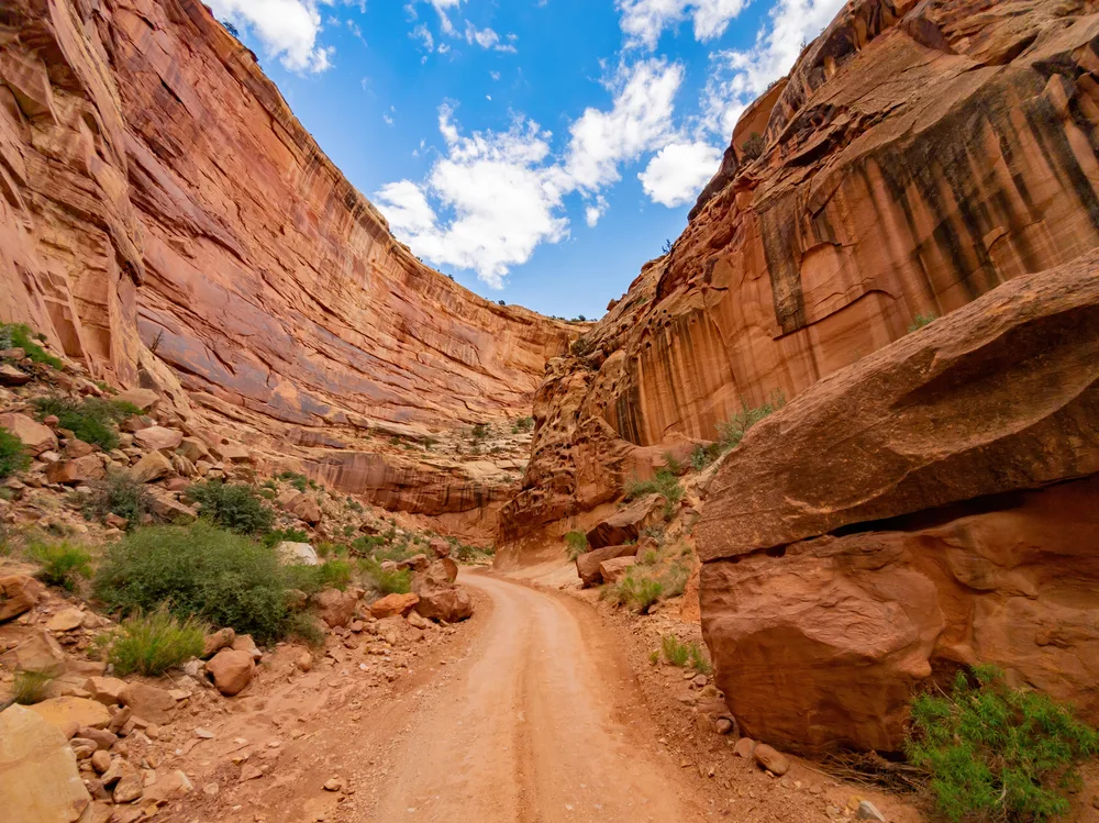 Red rock walking path going through a valley in between the jagged cliffs in Capitol Reef National Park