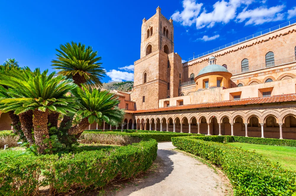 Old cathedral with arches and a gorgeous garden in Monreale, one of the best places to visit in Sicily