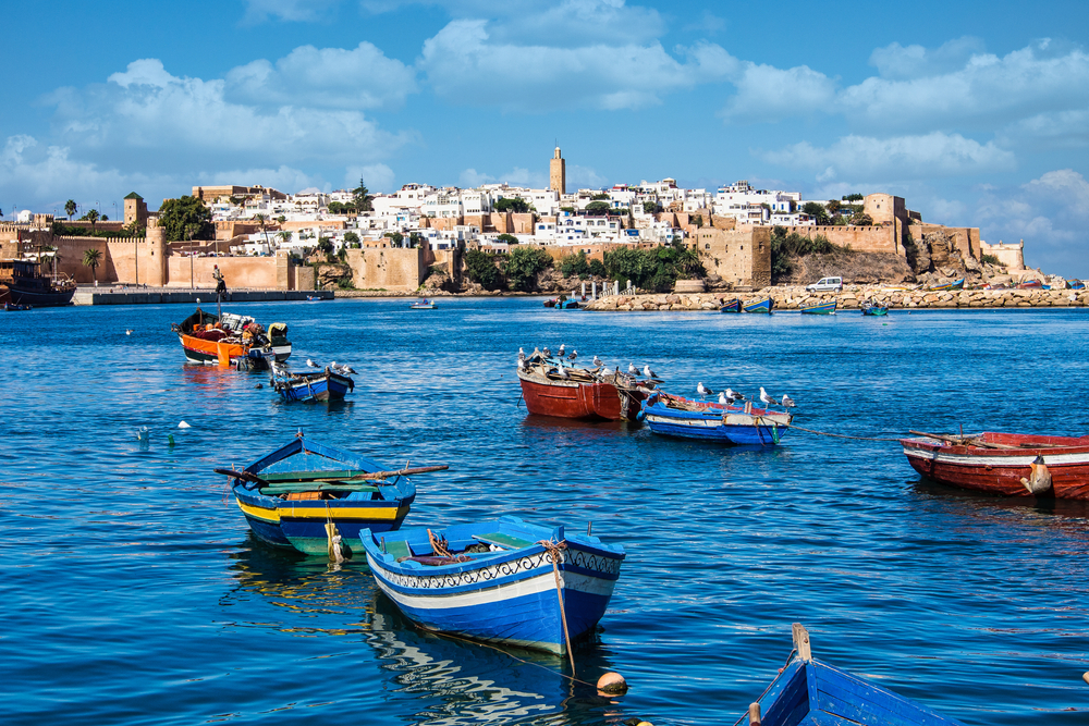 View from the harbor of Rabat, one of our top picks for must-see places in Morocco, with colorful rowboats floating on the mostly still water