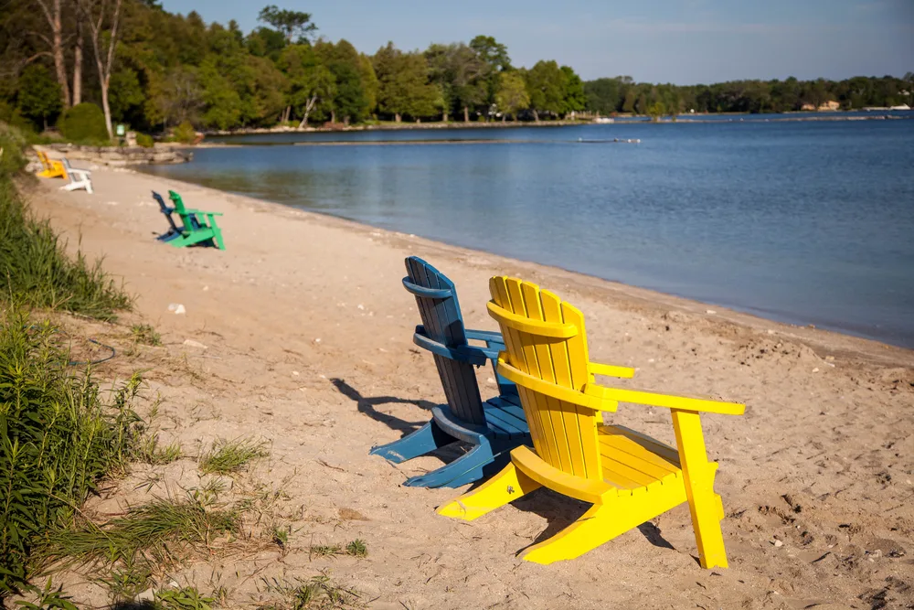 Adirondack chairs on the shore of a sandy beach in Wisconsin during the best time to visit Door County