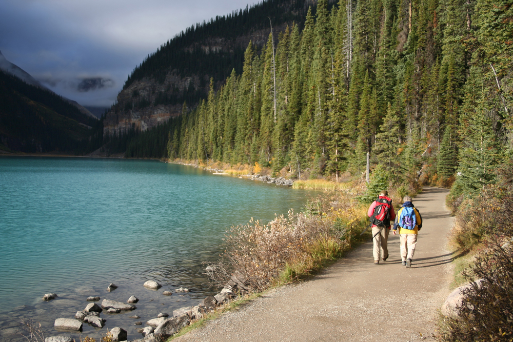 Elderly couple in hiking clothes walking along Lake Louise during the least busy time to visit, the late winter