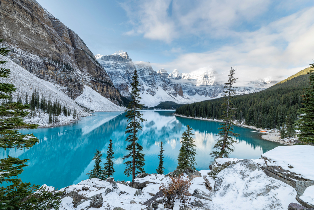 Teal lake below the mountains in the valley with fog covering the top of the mountains for a piece on the best places to visit in December
