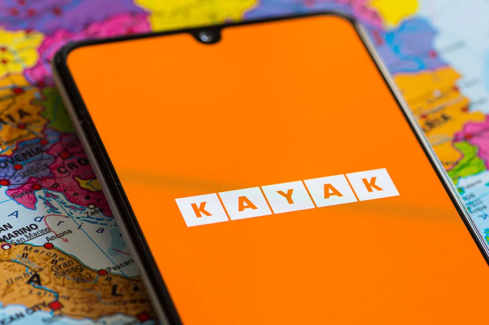 Orange Kayak logo and app screen on a smartphone lying on a map for a piece on the best hotel booking sites for travelers