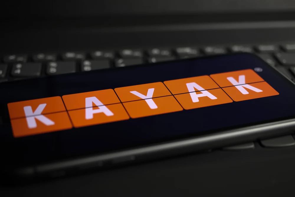 Orange and white Kayak logo on a black keyboard shows one of the best websites to book flights