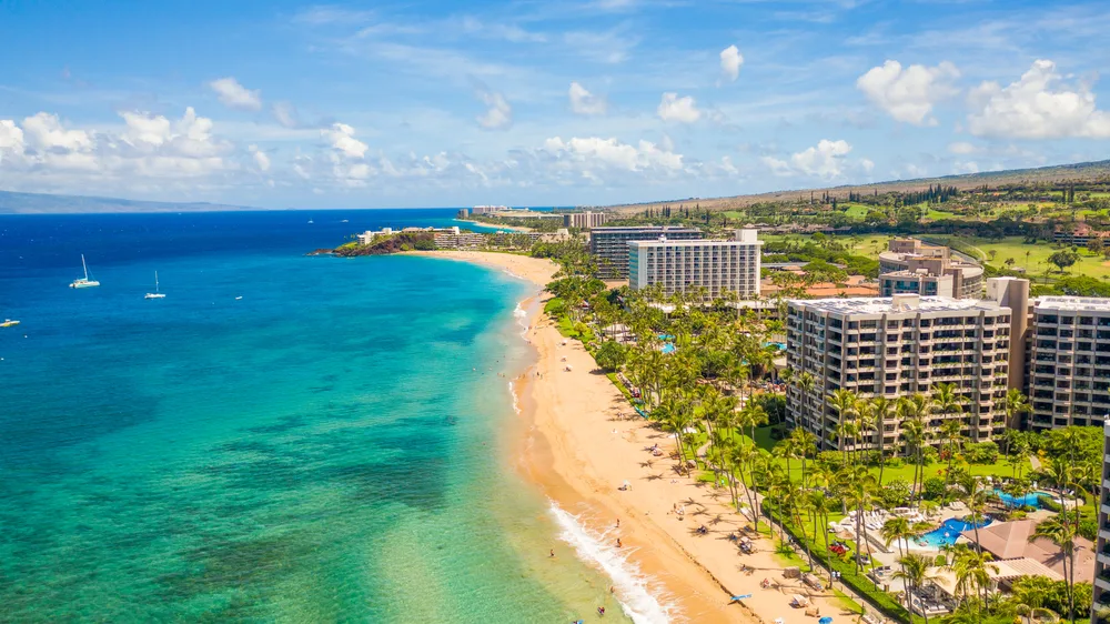 Aerial view of hotels and resorts on Maui in Hawaii with tourists on the beach and clear ocean water for a list of places to go in May