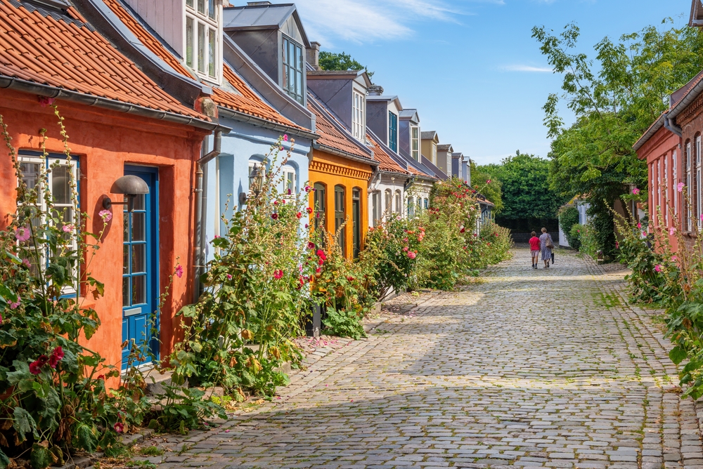 Colorful cottages on either side of a brick pathway pictured on a clear day during the least busy time to visit Denmark