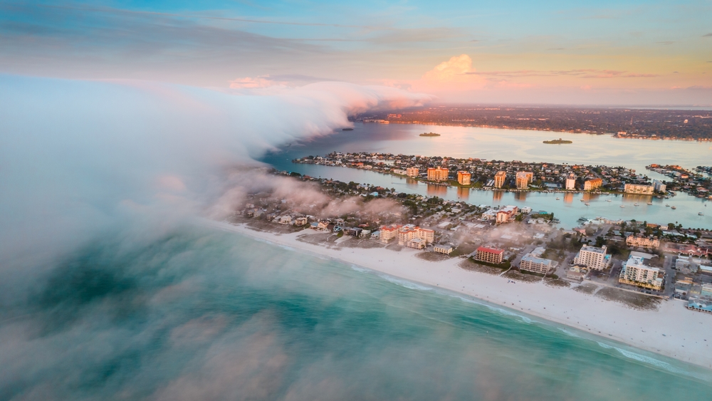 Rain cloud with fog rolling over Clearwater during the worst time to visit with water and sand below