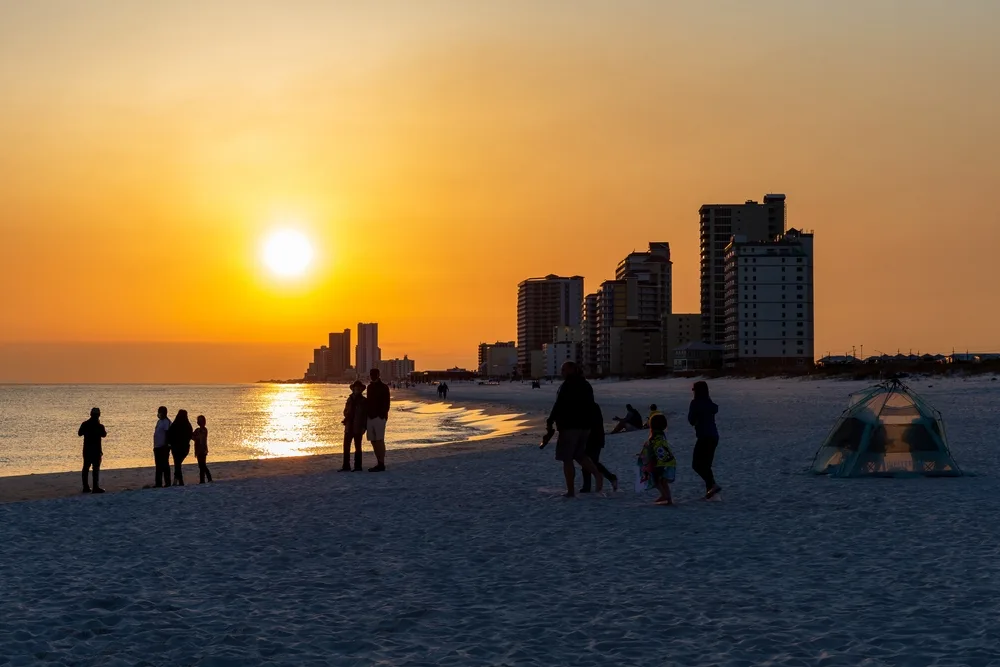 People walking along a beach at dusk during the overall cheapest time to visit Gulf Shores Alabama