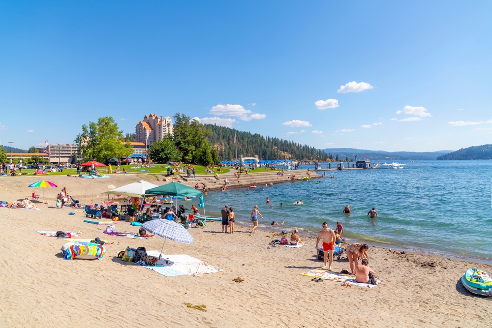 For a guide titled Best Time to Visit Idaho, a photo of the sandy beaches of Coeur d'Alene