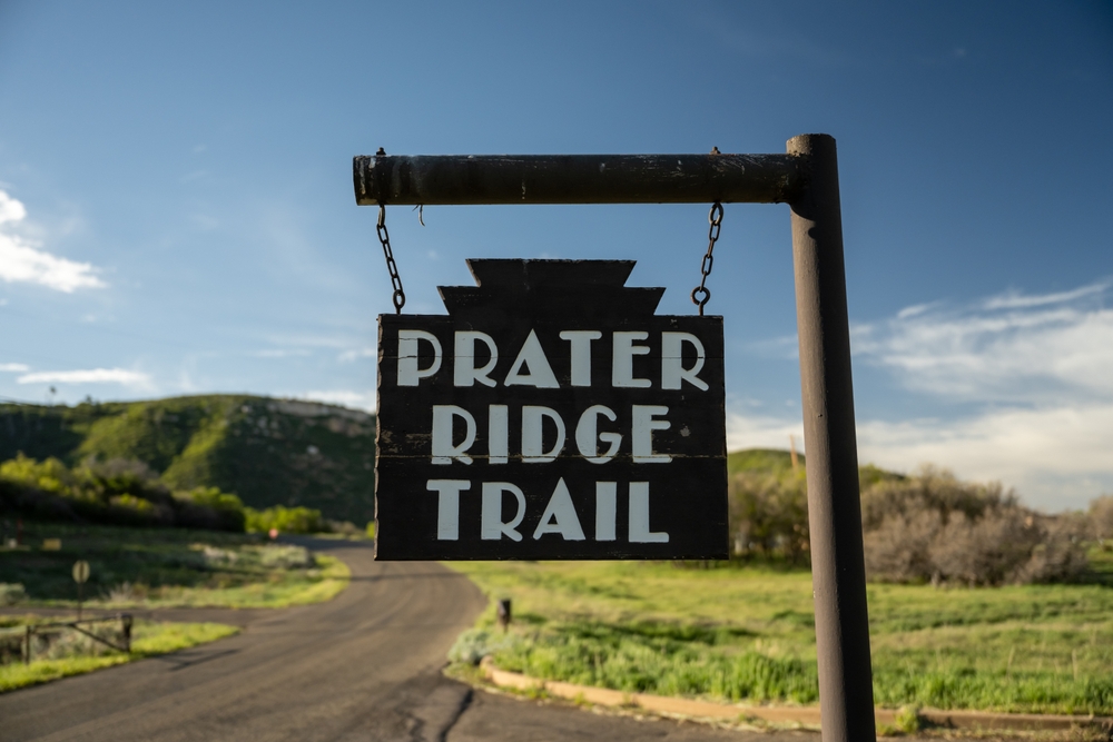 Prater Ridge Trail seen in an up-close image with expansive mountains behind it and blue skies overhead