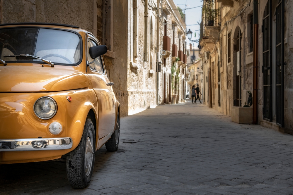 Neat head-on view of an orange car pictured in the middle of Syracuse, Sicily