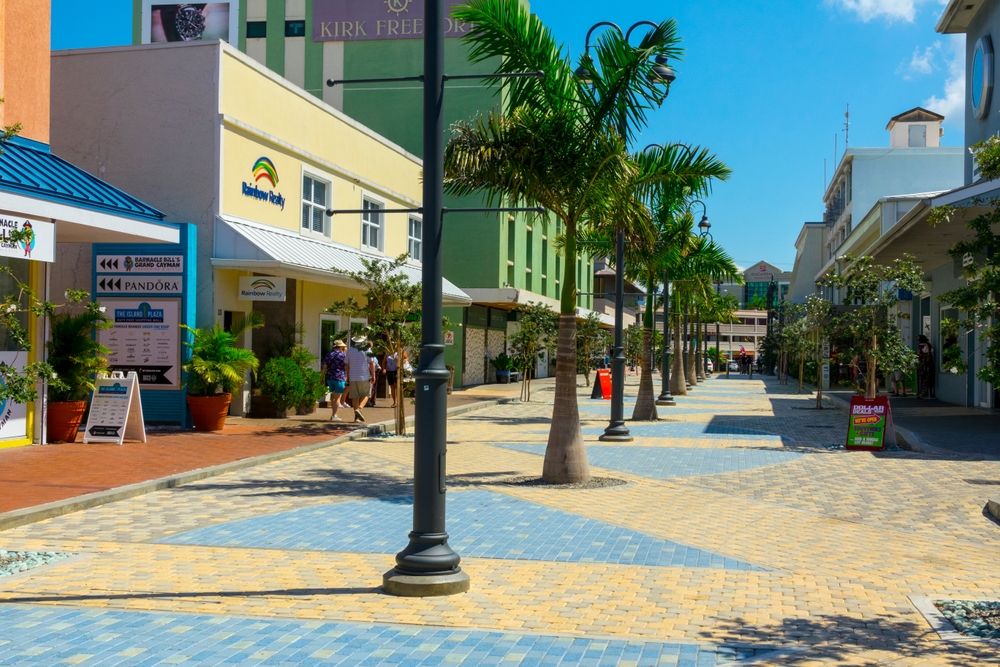 Pictured during the best time to visit Grand Cayman, a bunch of shops lining a colorful road in George Town