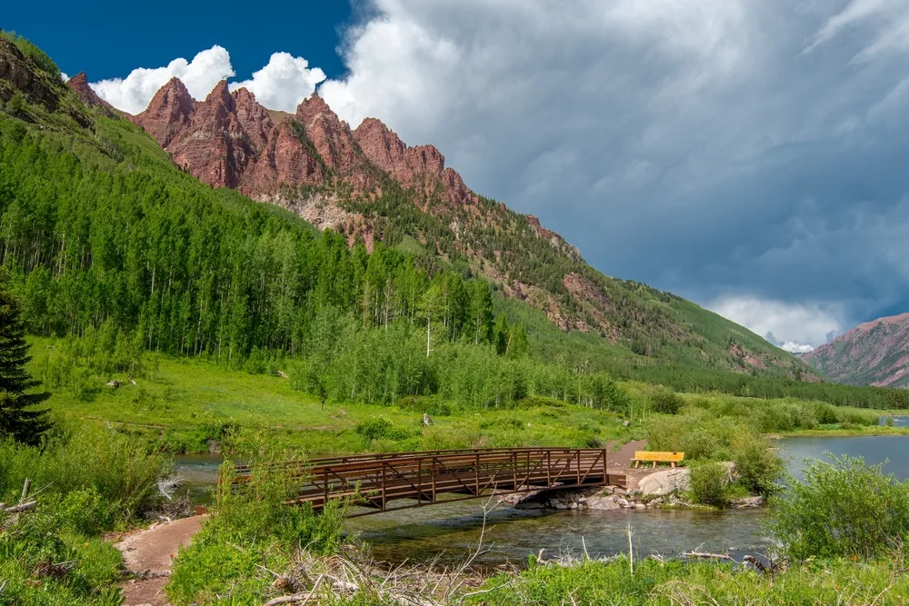 Gorgeous green trees in the middle of the mountains pictured for a guide titled Best Time to Visit Maroon Bells